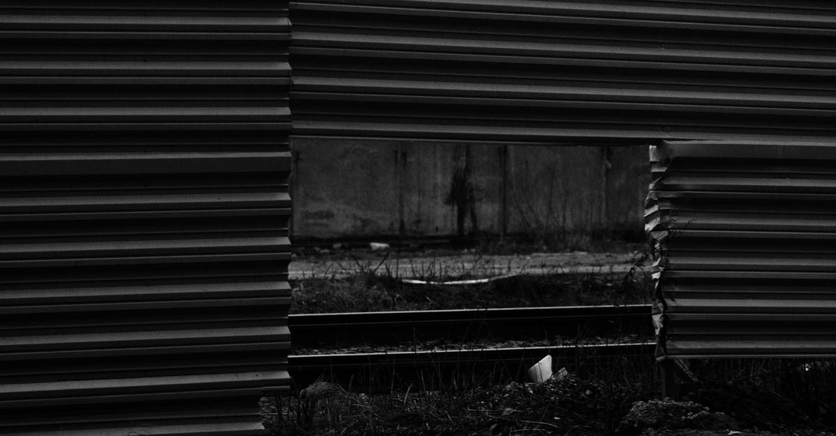 Transiting through Canada without going through border control [duplicate] - Black and white of automobile road and rails visible through square hole in lower part of enclosure from metallic profile