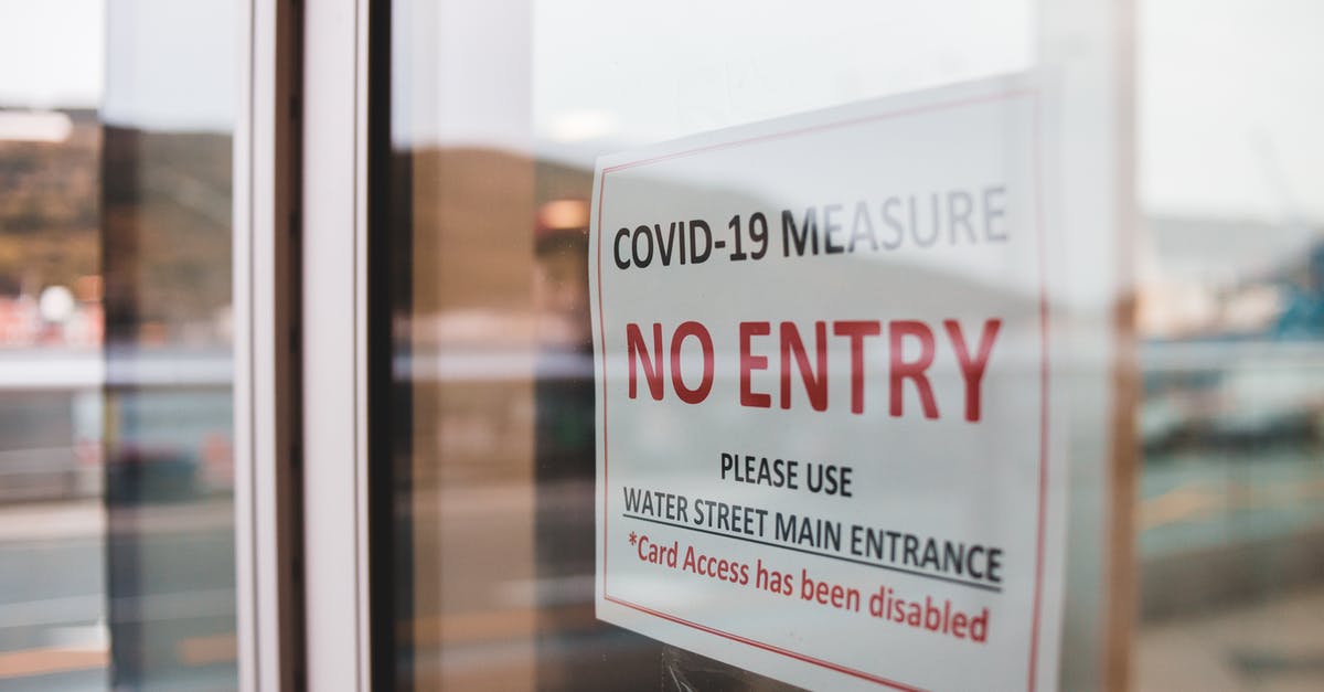 Transiting through Italy: Covid-19 restrictions - Warning signboard on glass door in street