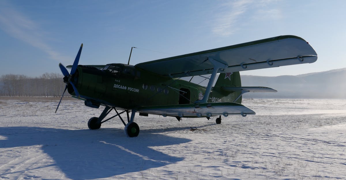 Transport frozen mother's milk by plane - Soviet aircraft with propeller placed on snowy ground of airfield against cloudless blue sky on cold winter day in countryside