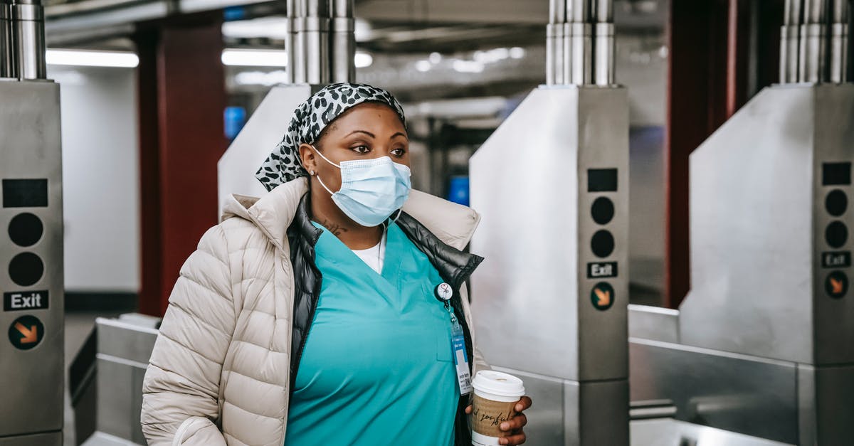 Transport pass for one week in Mallorca - Black nurse in outerwear and mask passing turnstile in underground