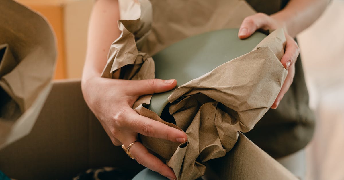 Transporting fragile ceramics in carry-on with Ryanair - Crop woman with packing paper and belongings