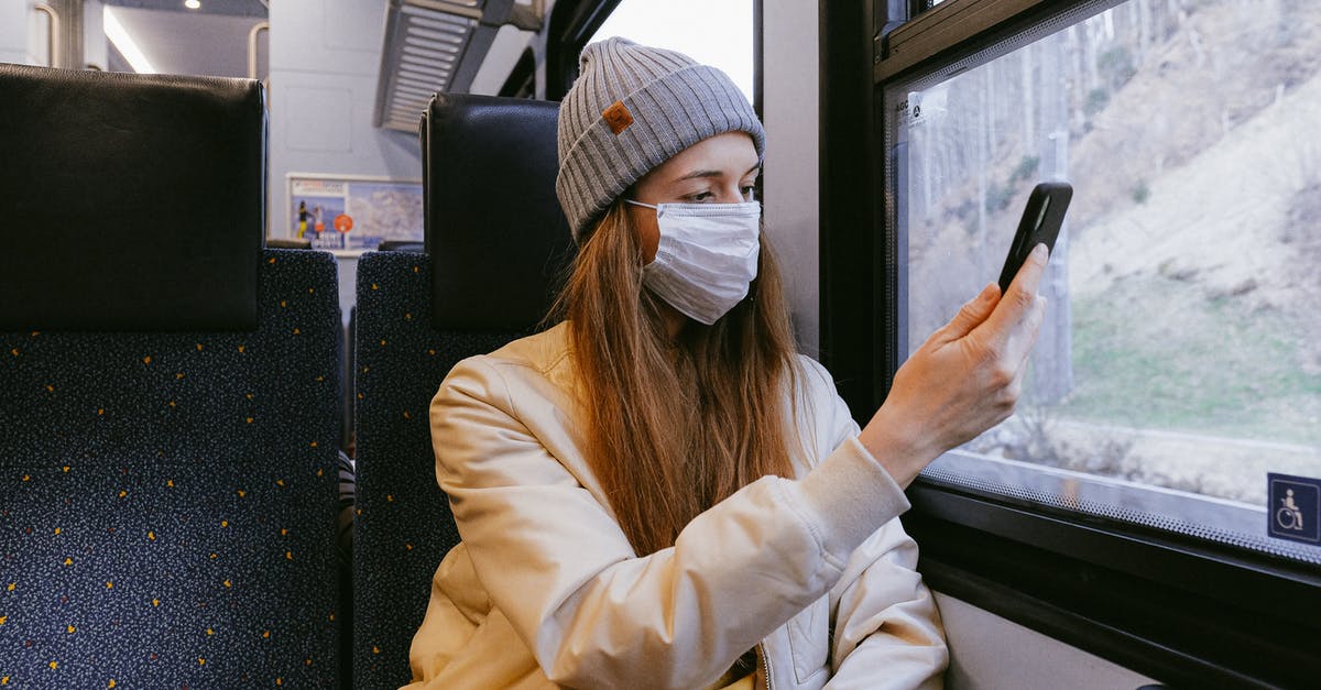 Travel by train in the UK using my senior railcard - Woman in Beige Jacket and Gray Knit Cap Holding Smartphone