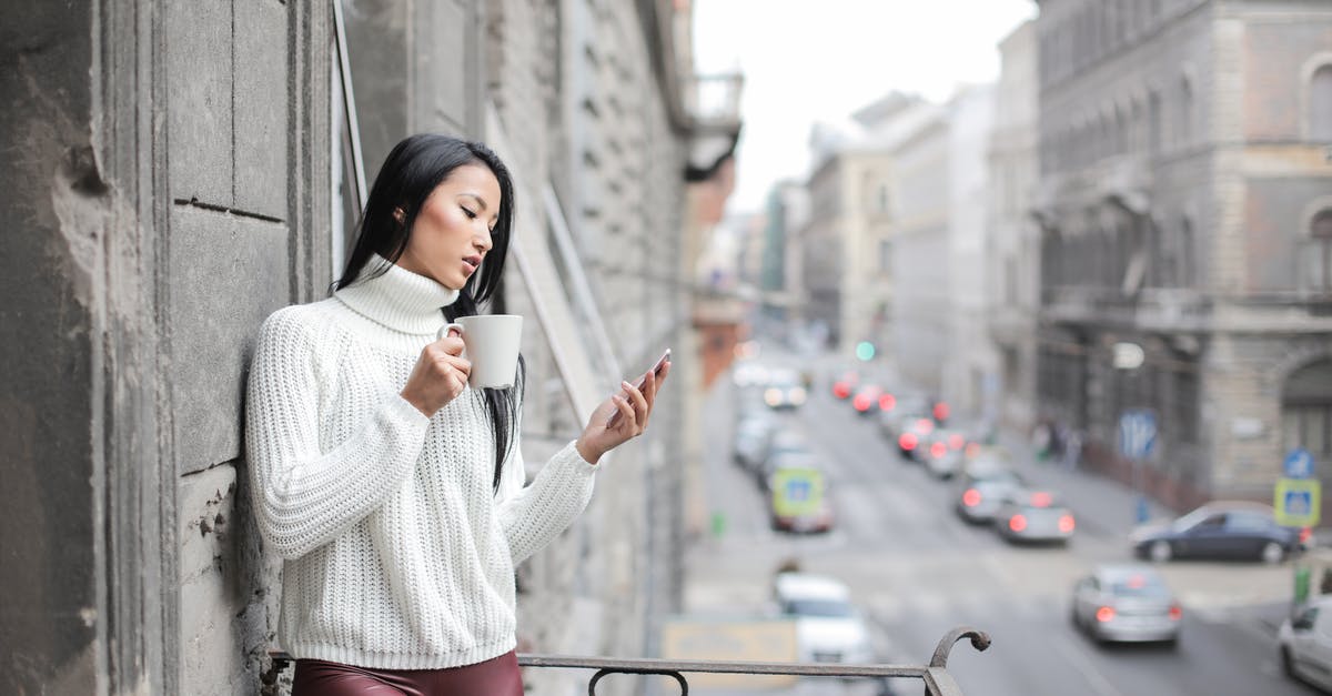 Travel Portable Battery - Woman in White Sweater Holding A White Ceramic Cup