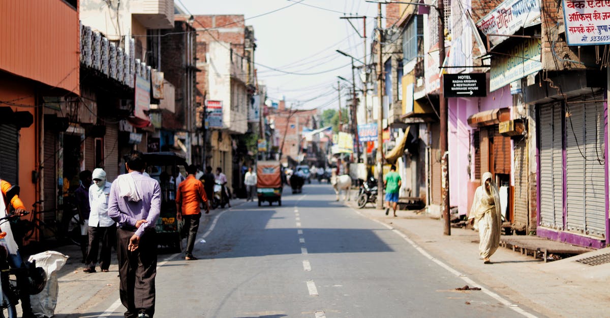 Travel to the EU as dual citizen [duplicate] - Citizens walking along street with shabby buildings and tuc tuc bikes parked on roadside in poor area of Asian town on sunny weather