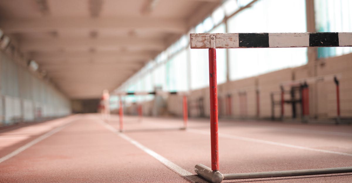 Travel within the Schengen area with Fiktionbescheinigung - Hurdle painted in white black and red colors placed on empty rubber running track in soft focus
