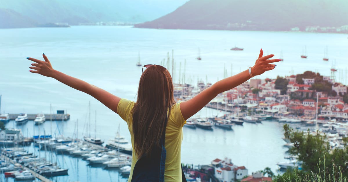 Traveling aboard an ocean liner like in The Royal Tenenbaums? - Woman Raising Her Hands Facing Cityscape Near Body of Water