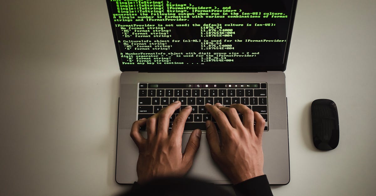 Traveling abroad with high end cryptography devices and software - From above crop anonymous male programmer in black hoodie working on software code on contemporary netbook and typing on keyboard in workspace