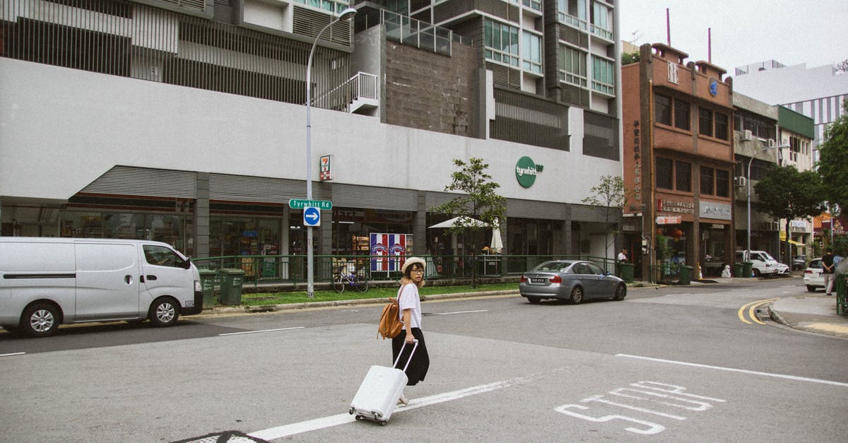 Traveling from Asia and transiting though Vancouver to Portland - Woman Pulling Luggage Bag While Walking Toward Building