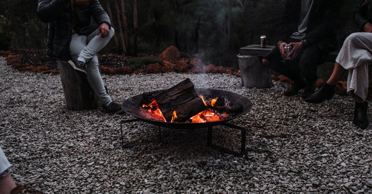 Traveling from cold region to warm region; tips regarding clothing? - Unrecognizable travelers sitting near campfire in woods