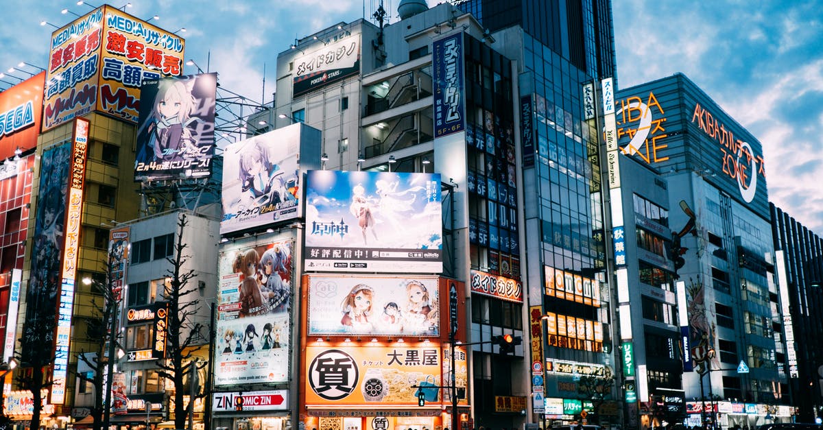Traveling from San Francisco to Tokyo with a peculiar medical condition - Low angle exteriors of contemporary buildings with colorful signs and monitors located in Tokyo downtown against cloudy blue sky