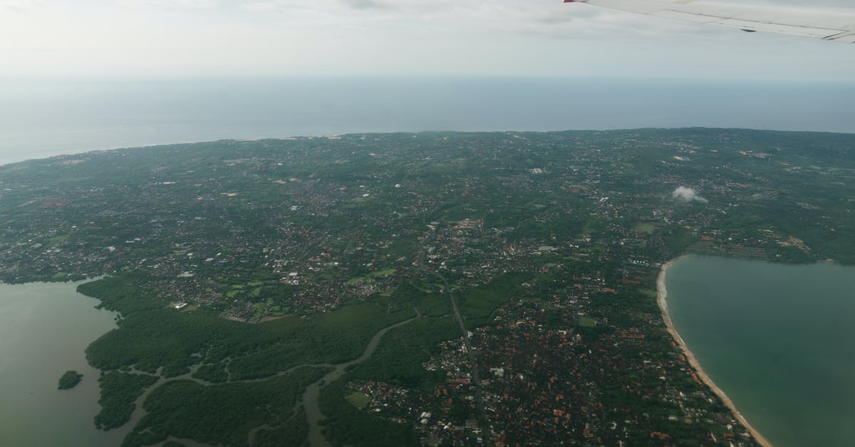 Traveling to cities with extremely high air pollution - Wing of aircraft flying over coastal city