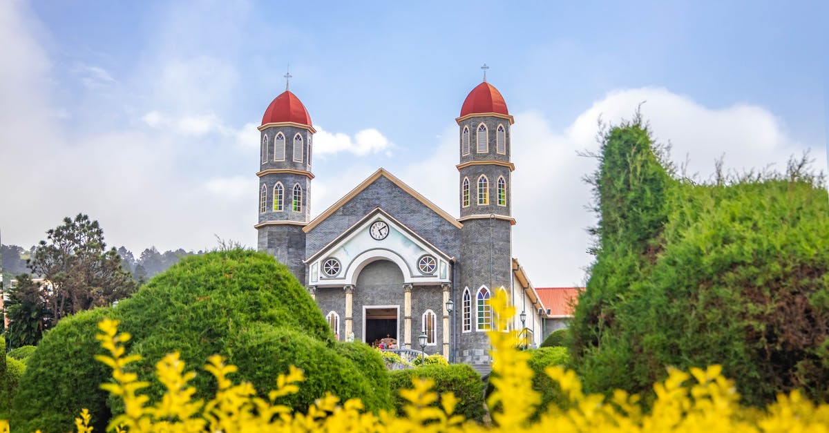 Traveling to Costa Rica - Old Catholic church in well maintained garden against blue sky