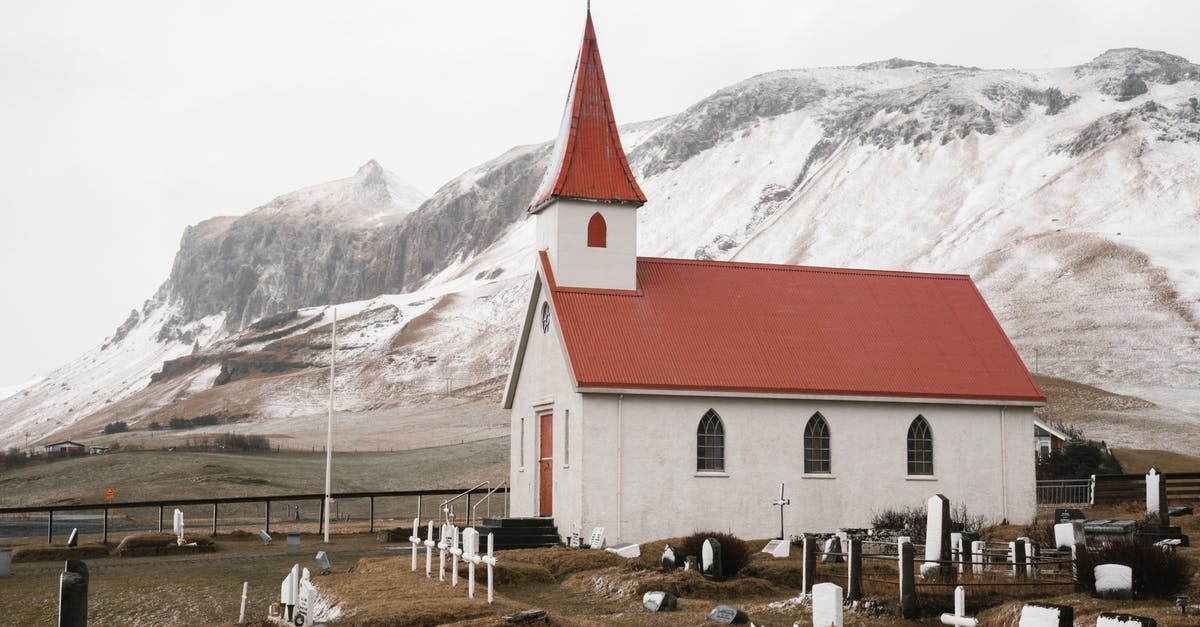 Traveling to Northern Kosovo (e.g. Zubin Potok) [duplicate] - Dyrholaey Church and quiet churchyard with cemetery near magnificent snowy mountains on cloudy autumn day in Iceland