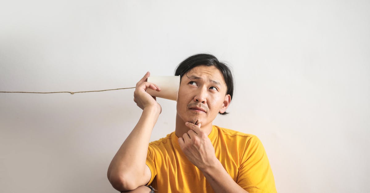 Traveling to Seoul, phone questions - Pensive ethnic man listening to answer in paper cup phone