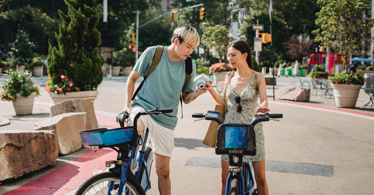 Traveling to Thailand, immigration and customs check 3 times? - Multiracial friends riding on bicycles with camera in park with green plants in sunny weather in summer