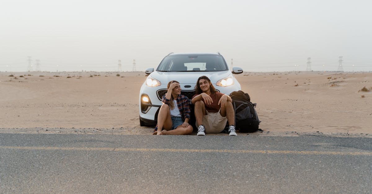 Travelling as unmarried couple in Dubai - Man and Woman Holding a Map While Standing In Front of the White car