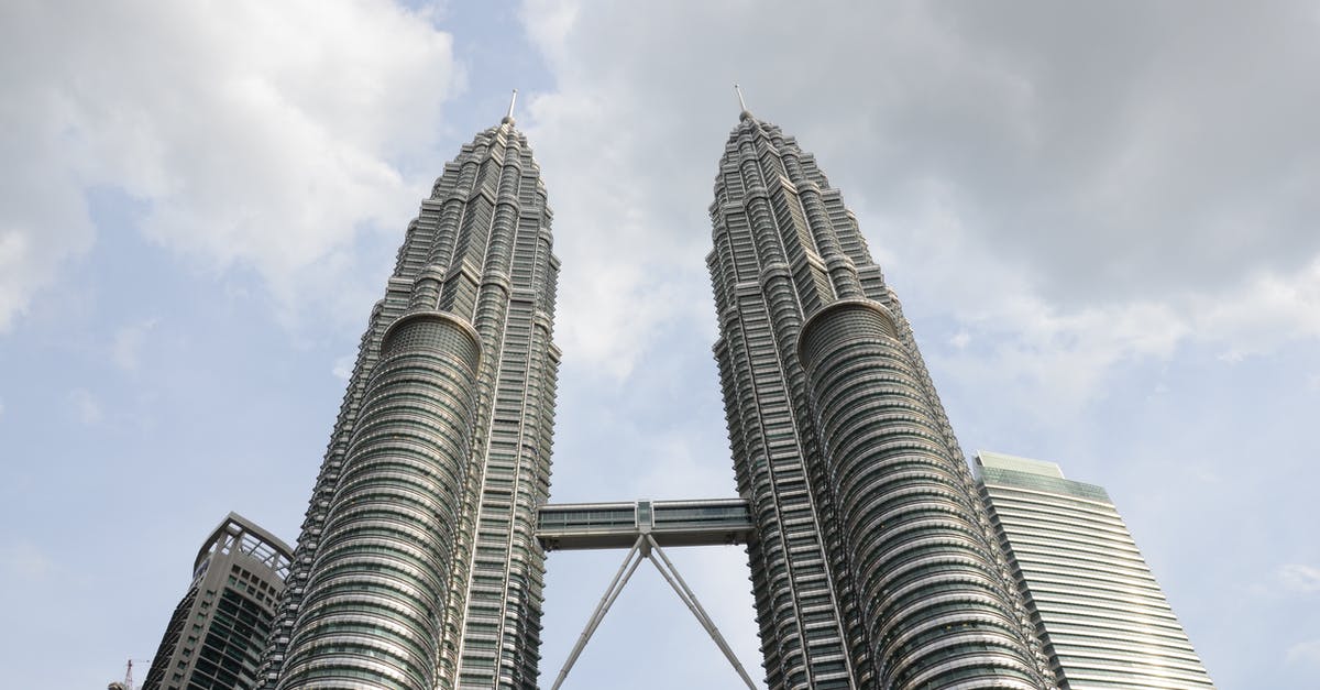 Travelling from Phuket,Thailand to Malaysia with Visa - From below tall futuristic twin towers with steel and glass facade located against cloudy sky in Kuala Lumpur