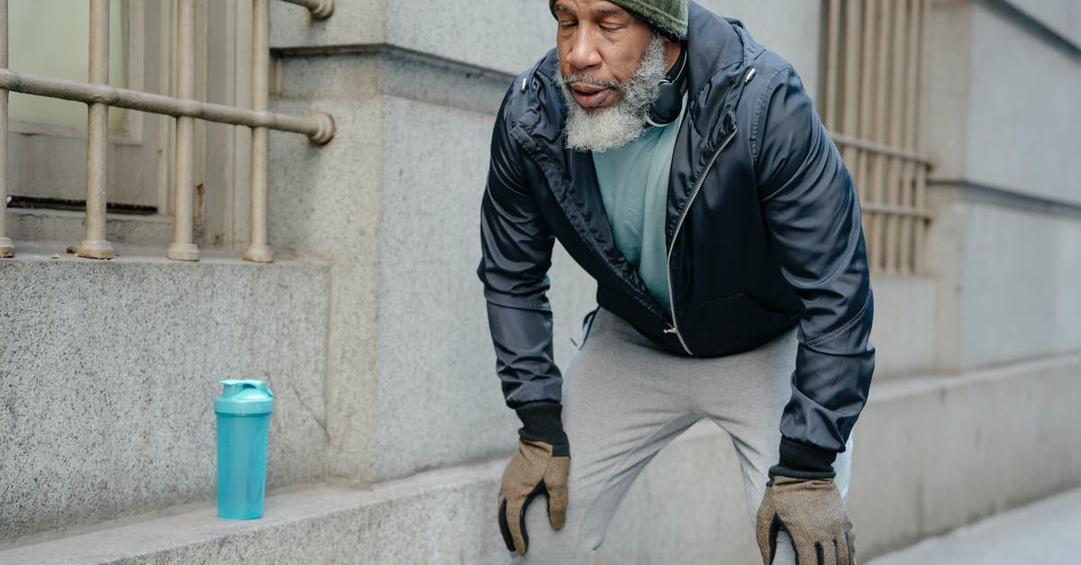 Travelling outside the USA while on Optional Practical Training (OPT) [closed] - Concentrated bearded senior black man wearing warm sportswear leaning forward with hands on knees and closed eyes in street near building while break in workout