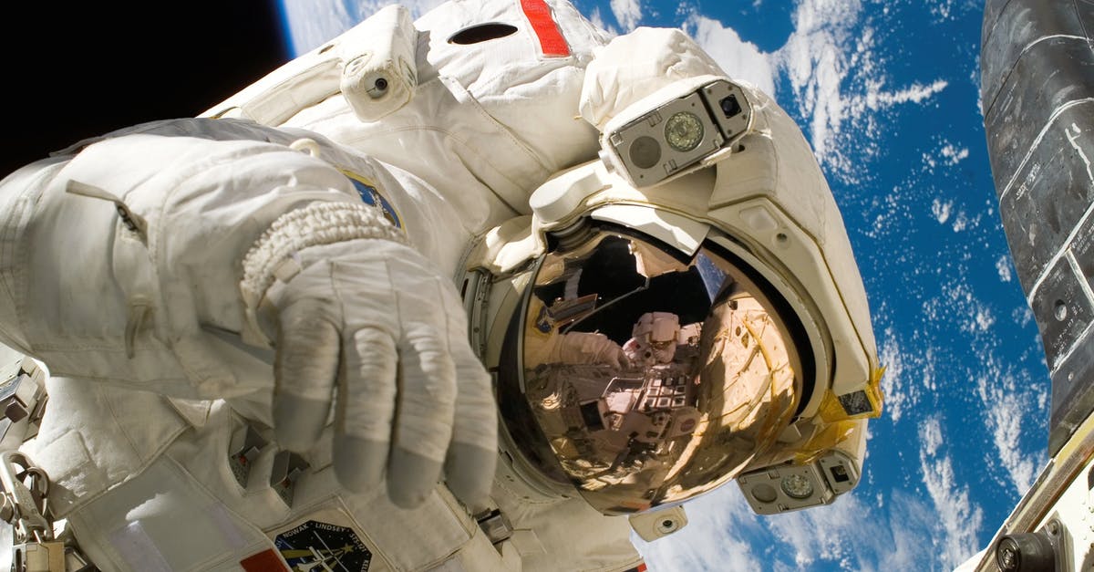 Travelling through the US with Canadian Working Visa - This picture shows an american astronaut in his space and extravehicular activity suite working outside of a spacecraft. In the background parts of a space shuttle are visible. In the far background of the picture planet earth with it's blue color and whi