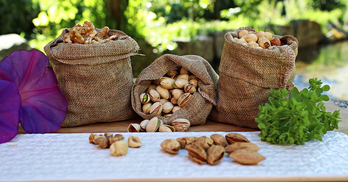 Travelling to Asia and Oceania with a peanut and pistachio allergy - Jute sacks with pistachios walnuts and peanuts placed on wooden table in park near pond on sunny day