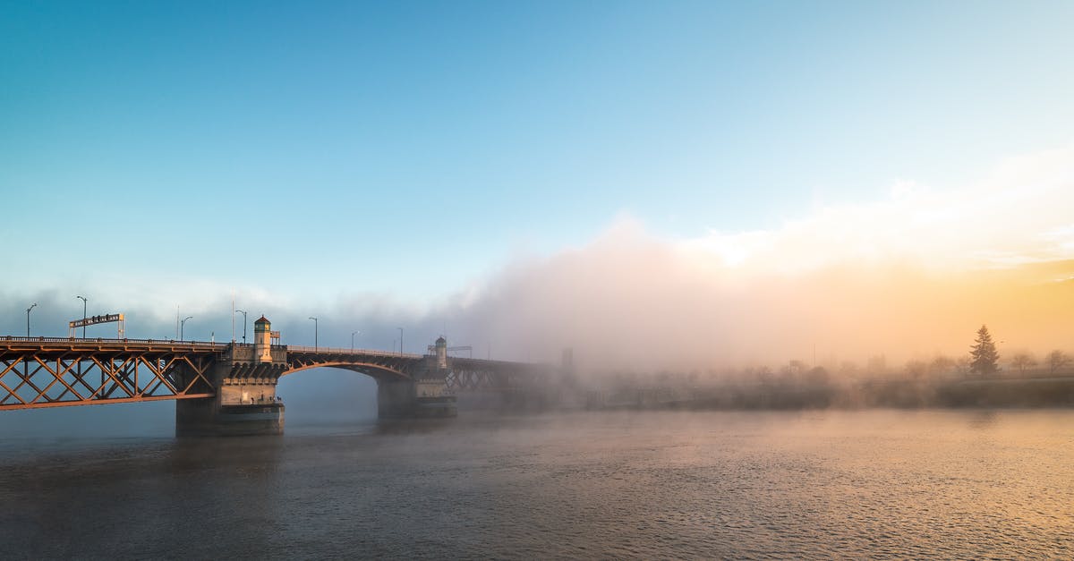Travelling to Bend, Oregon from Portland in winter - Magnificent scenery of famous Burnside Bridge crossing rippling river and hidden under fog against colorful sunset sky