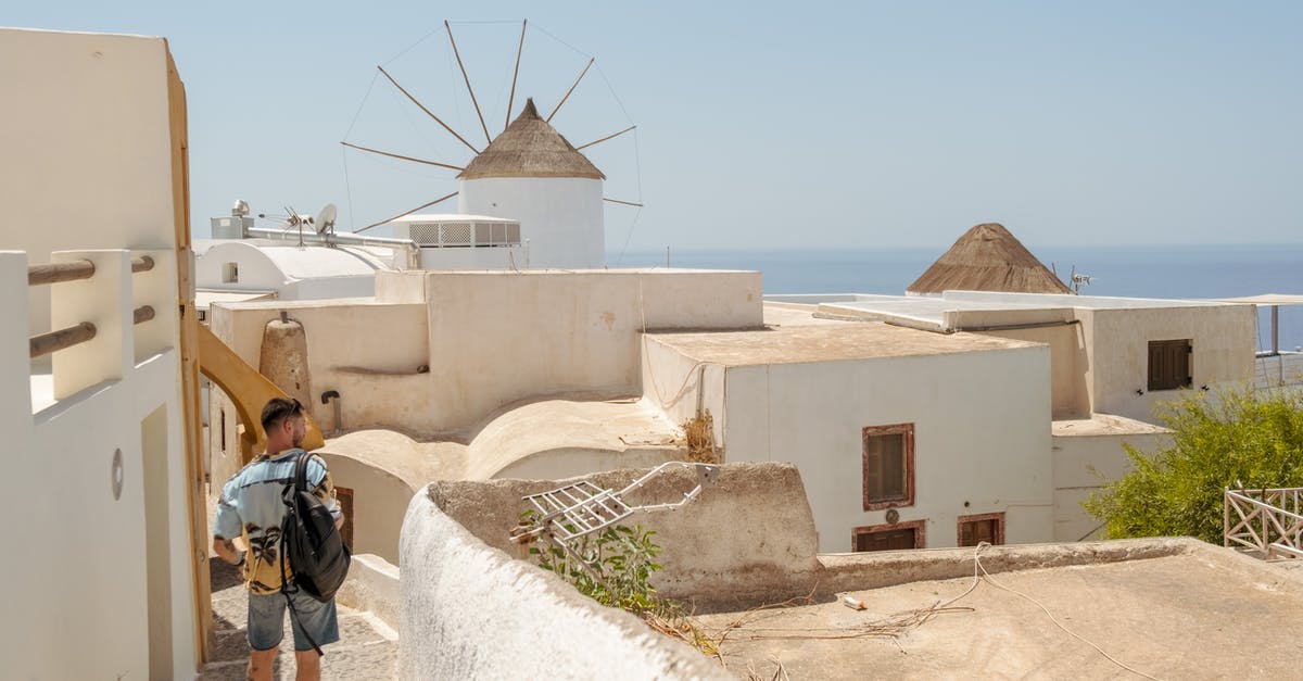 Travelling to Greece without knowing the language - Man in Black Jacket Walking on White Concrete Pathway