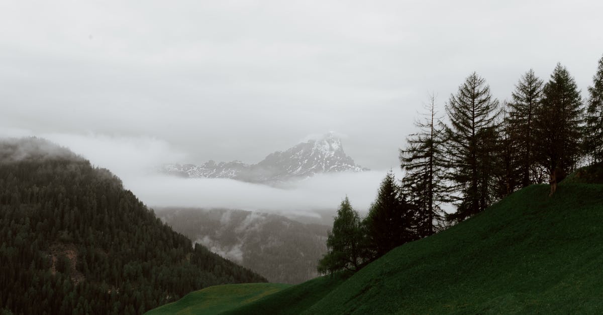 Travelling to Kiruna, Sweden from Dubai, clothing during extreme cold climate - Majestic landscape of high mountains covered with spruce trees and snow against gray foggy sky