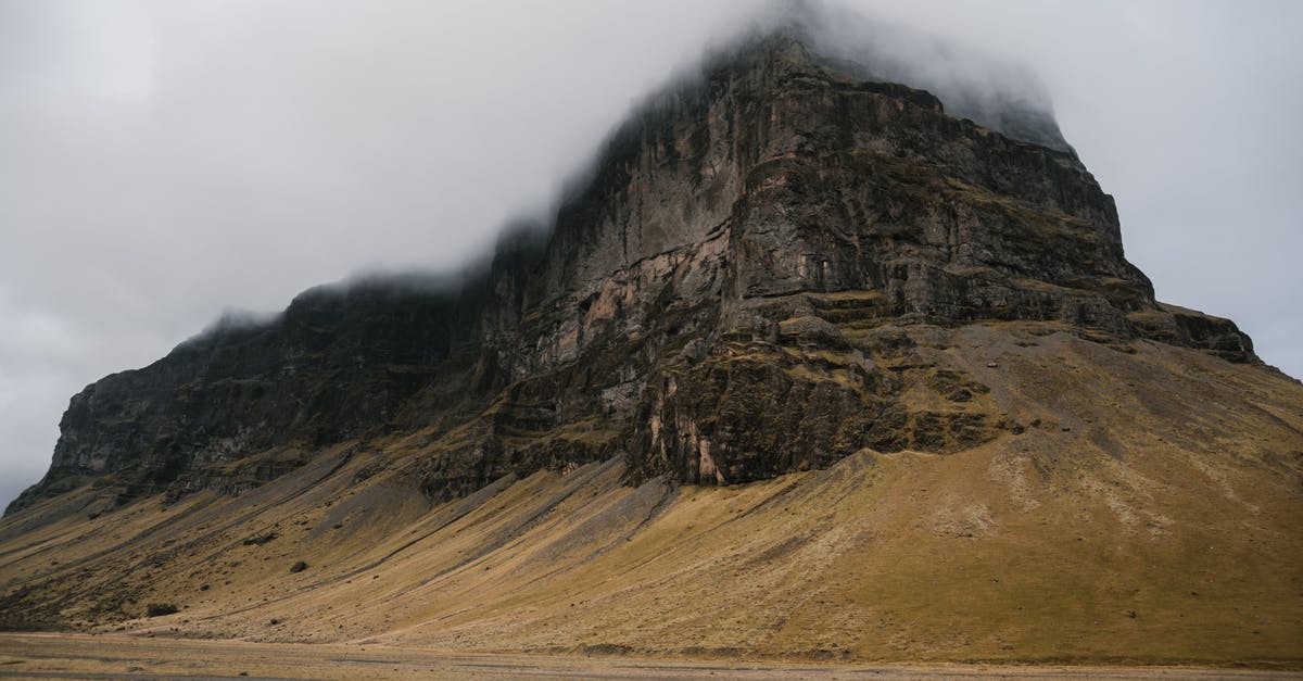 Travelling to Kiruna, Sweden from Dubai, clothing during extreme cold climate - Picturesque view of rough rocky table mountain covered with rare vegetation with top hiding in fog in cold overcast day