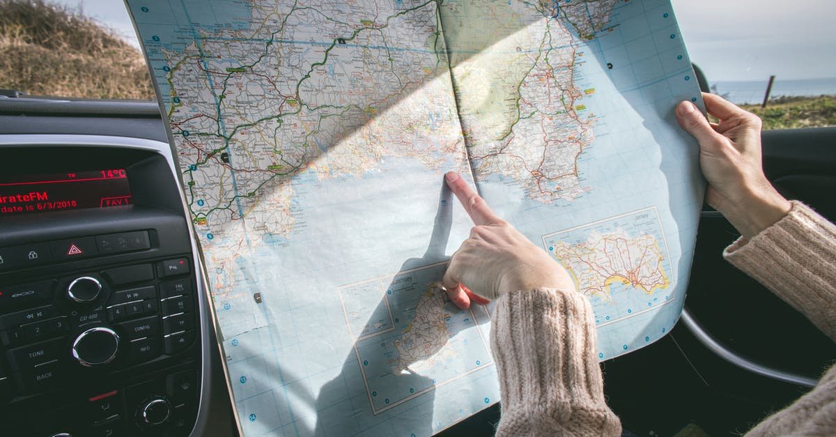 Travelling to Kuwait by Road - Person Wearing Beige Sweater Holding Map Inside Vehicle