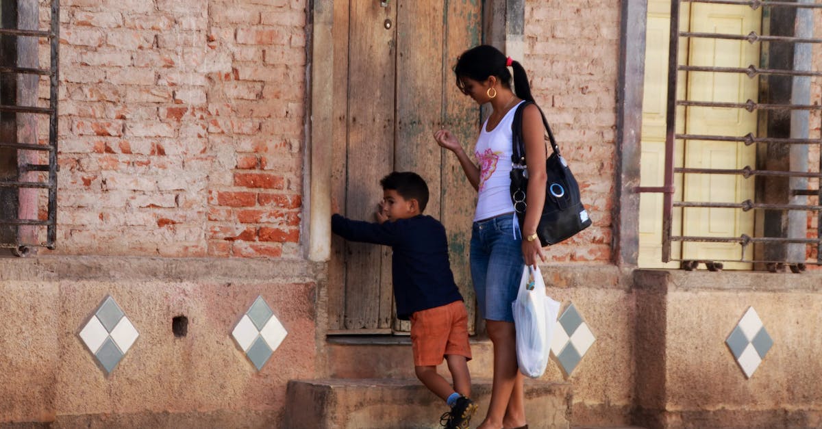 Travelling to Peru, Ecuador, Galapagos with kids - Woman in Blue Sleeveless Dress and Blue Denim Jeans Standing Beside Brown Wooden Door