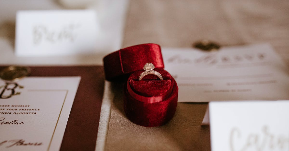 Travelling with expensive jewelries gift from my princess employer - Red box with golden ring placed on table with invitation cards