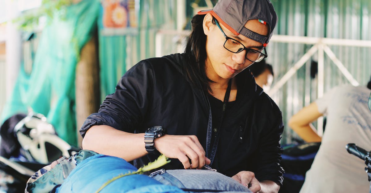 Travelling with hiking poles as checked-in luggage - Young ethnic man packing backpacks before trip