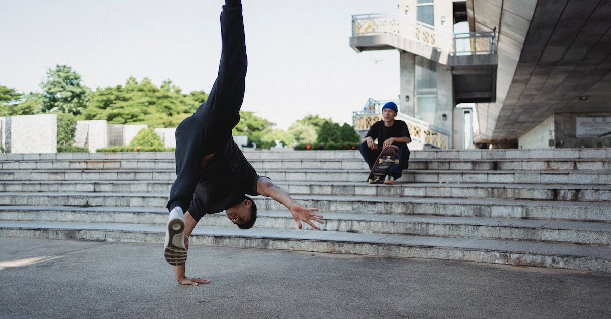 Trick to breaking down air routes - Ethnic dancer standing on hand near friend resting on staircase