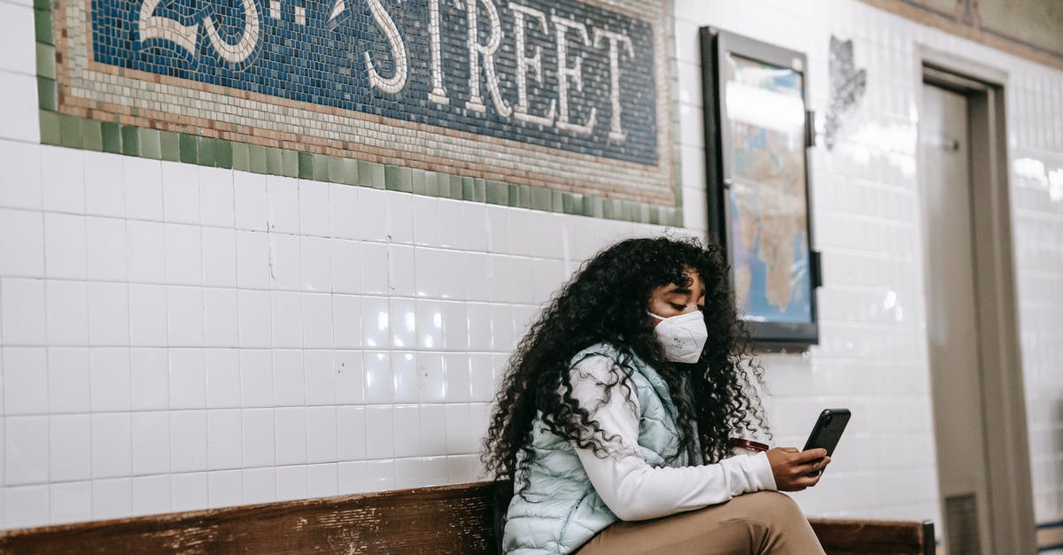 Trips betwen USA and China via Canada. Canadian transit visa needed? - Focused African American female in casual clothes browsing mobile phone while sitting on bench in New York underground platform