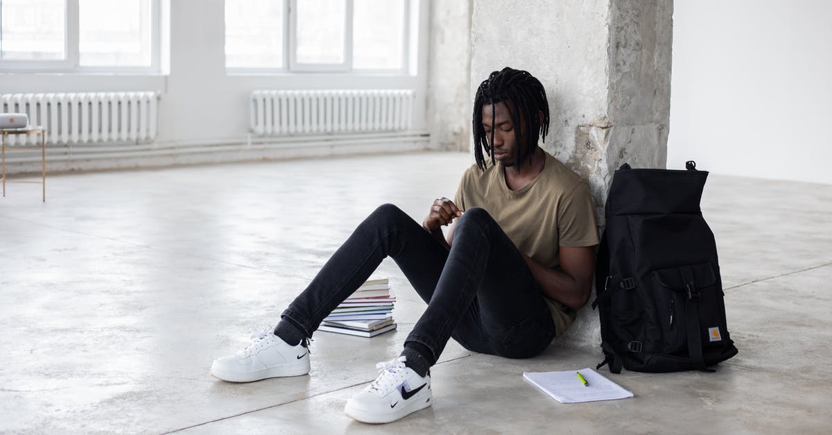 Trouble regarding Booking Tickets - Full body of upset African American man sitting among textbooks and notebook near backpack during break in exam preparation