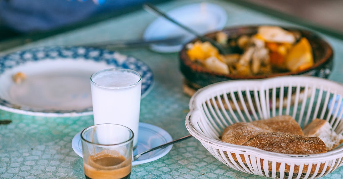 Trying local Romanian cuisine in Bucharest [closed] - Person eating traditional food with milk and coffee in glasses at table in daylight