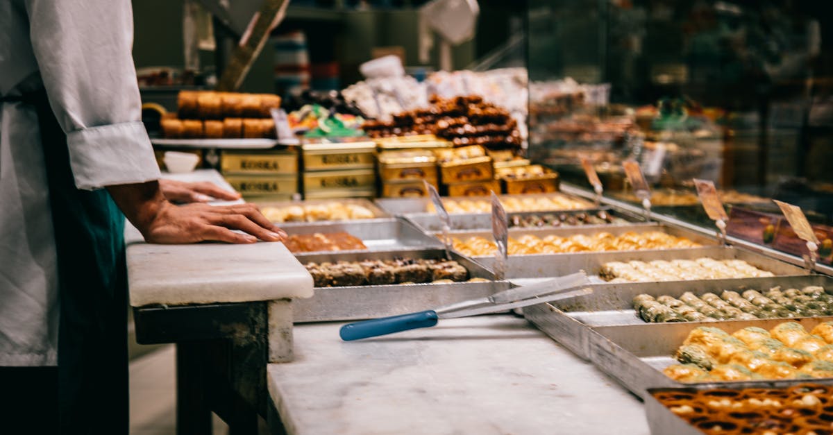 Trying local Turkish Cuisine in Istanbul - Crop anonymous male seller at counter with assorted traditional Turkish sweets in market