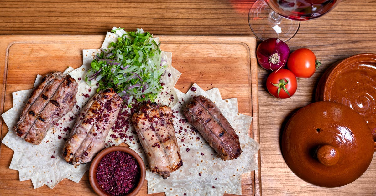 Trying local Turkish Cuisine in Istanbul - Sliced Meat With Green Vegetable and Red Tomato on Brown Wooden Chopping Board