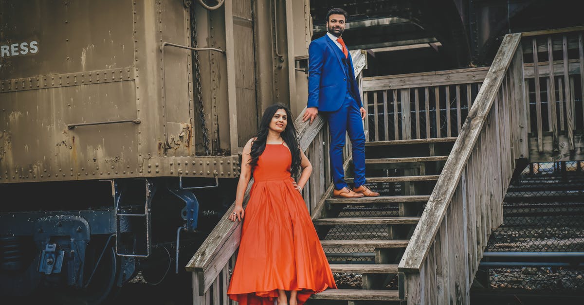 Trying to get on a full Indian Railways train - any strategies? - Full body of cheerful ethnic couple in red dress and blue suit near old train in railway station