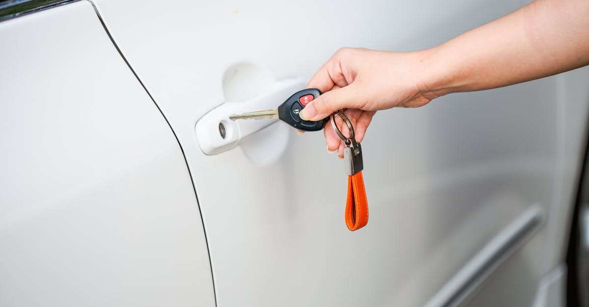 TSA unlock at airport? - A Person Holding a Car Key Near a Car Door