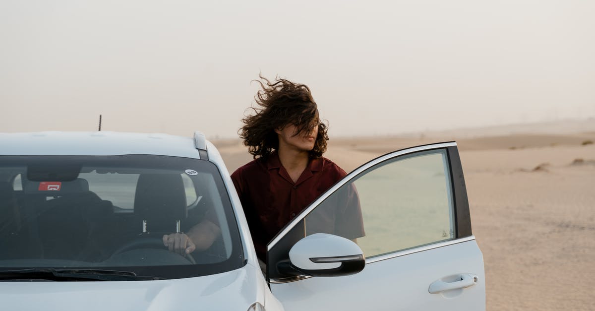 UAE Long Term Visa Validity [duplicate] - Man in the Desert Holding the Steering Wheel of a White Car