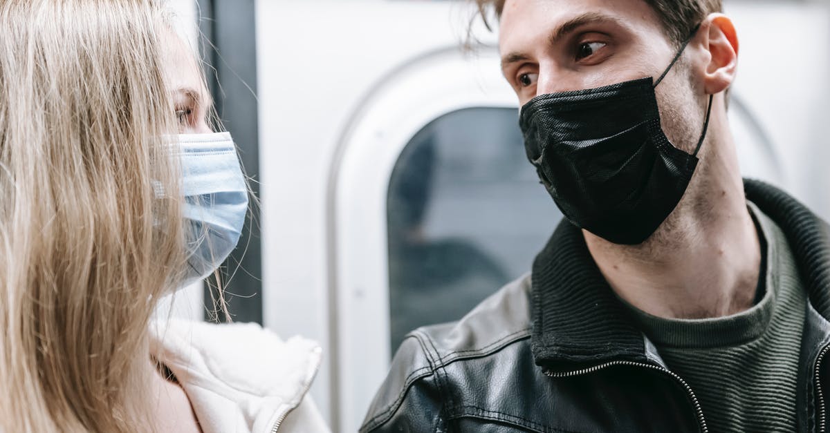 UK COVID Test-to-release programs starting date - Couple in medical masks standing in subway