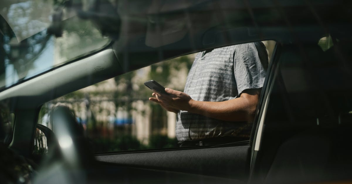 UK Marriage Visitor Visa application sending - Man using smartphone near taxi car