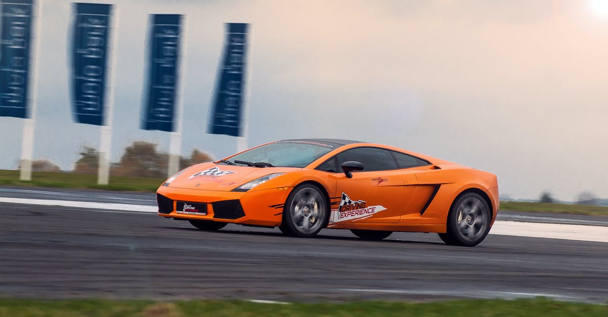 UK Motorways, Two Lane Slip Road Joins - Modern luxury orange sports car riding fast on asphalt highway at race at daytime under bright sky