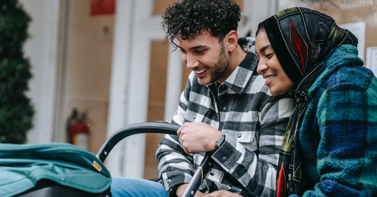 UK spouse, South African wife, Schengen visa - Cheerful young multiethnic spouses smiling and looking at baby in stroller