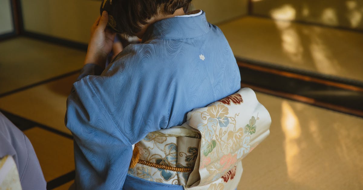 UK standard visitor visa for a Japanese national - Back view of unrecognizable person wearing authentic robe sitting on tatami while drinking tea from bowl during traditional Japanese ceremony