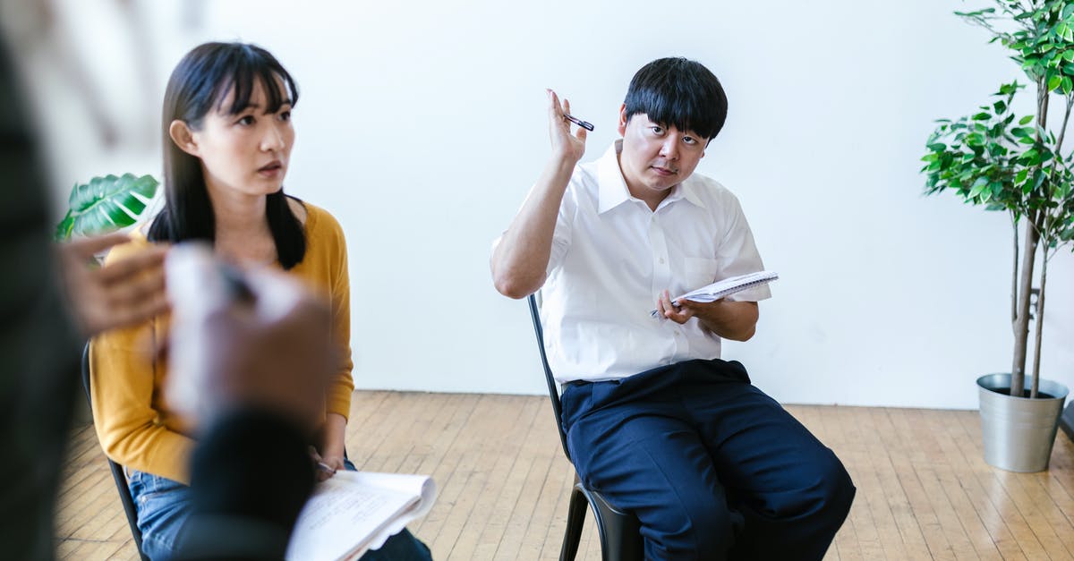 UK: Temporary Admission Question - Man in White Dress Shirt and Black Pants Sitting on Chair Beside Woman in Yellow T