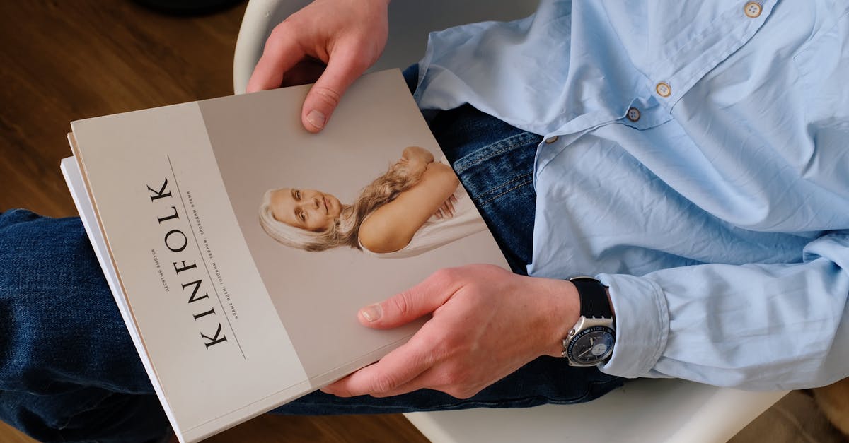 UK visa hotel booking and contact information - From above of unrecognizable man in casual clothes resting with magazine Kinfolk on knees while sitting on chair in modern studio