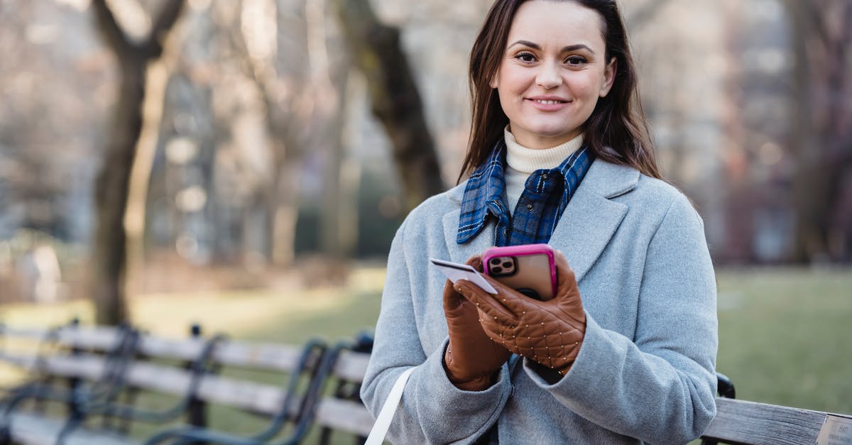 UK visa payment pending message - Smiling woman using smartphone on spring city park