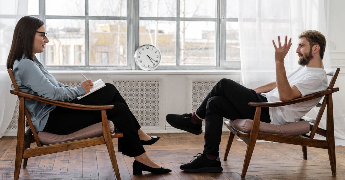 UK Visitors and NHS Health Services - Person in Black Pants and Black Shoes Sitting on Brown Wooden Chair